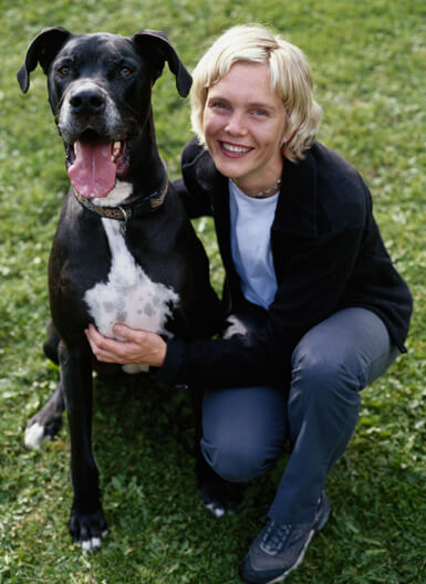 A lady on her knees with a huge black and white dog